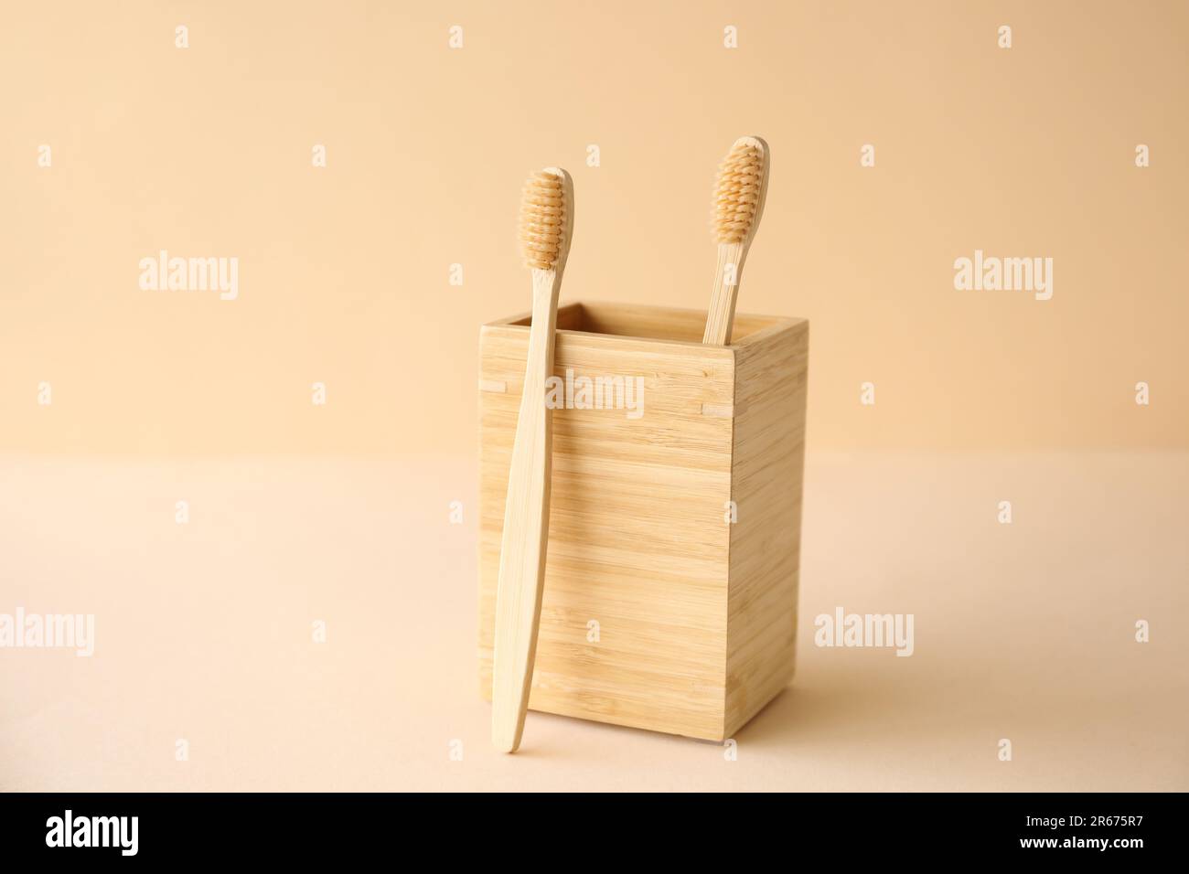 Bamboo tooth brushes and holder on beige background Stock Photo - Alamy
