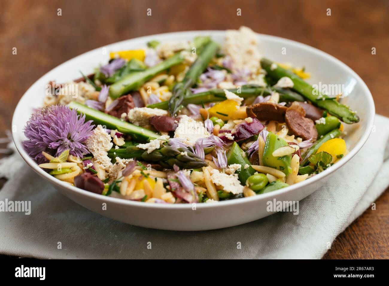 Bowl with a home made orzo salad with asparagus, fava beans and kalamata olives Stock Photo