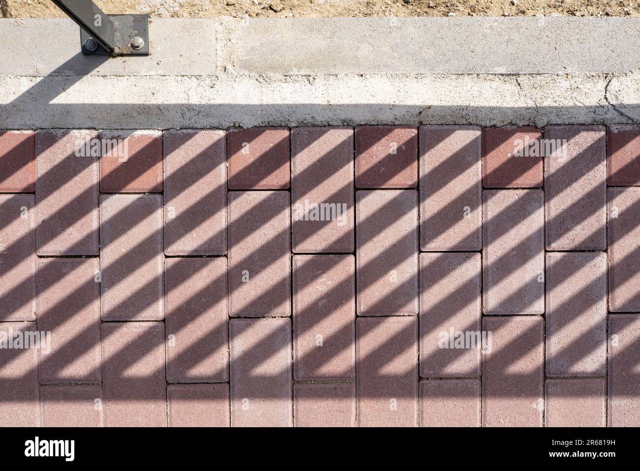 Brown colored paving bricks with shadows from a railing Stock Photo