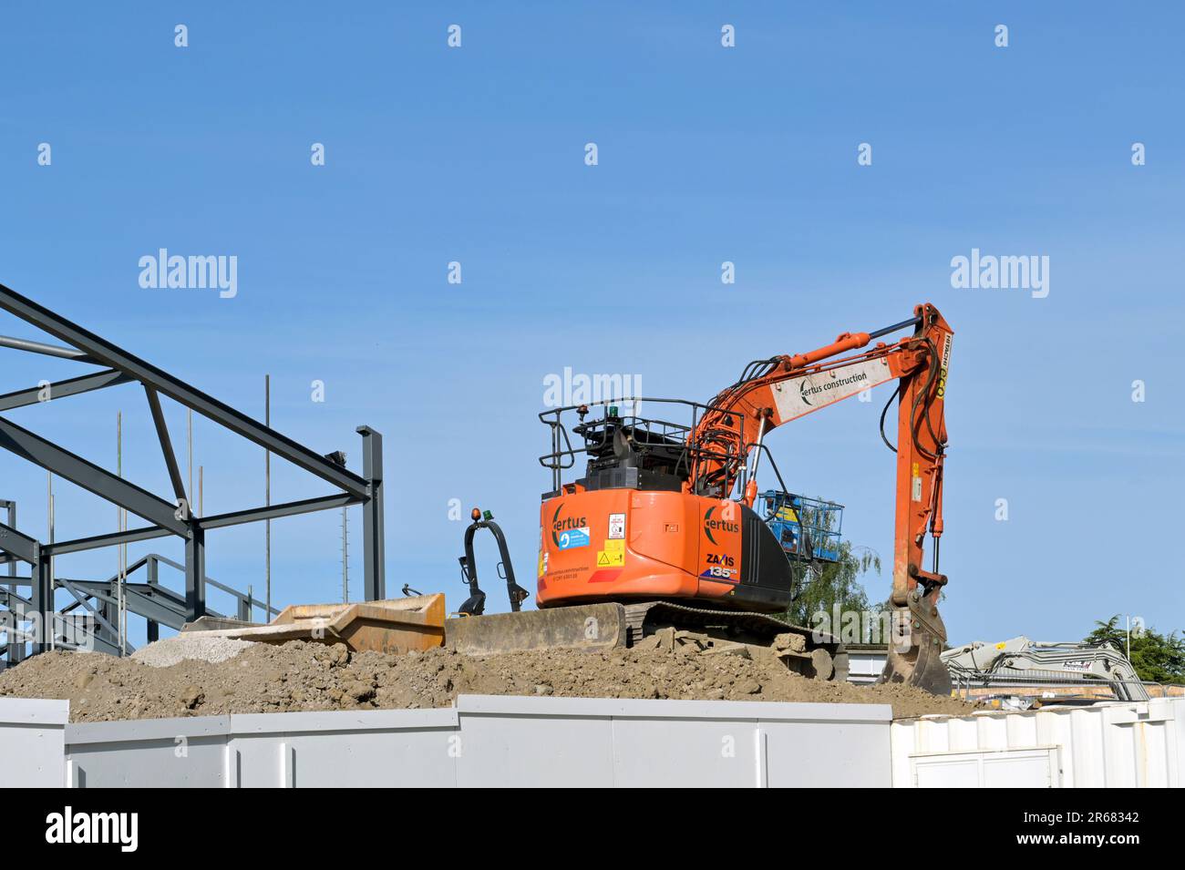 Church Village, Pontypridd, Wales - May 2023: Mini excavator on top of a pile of soil on the construction site for a new primary school in south Wales Stock Photo