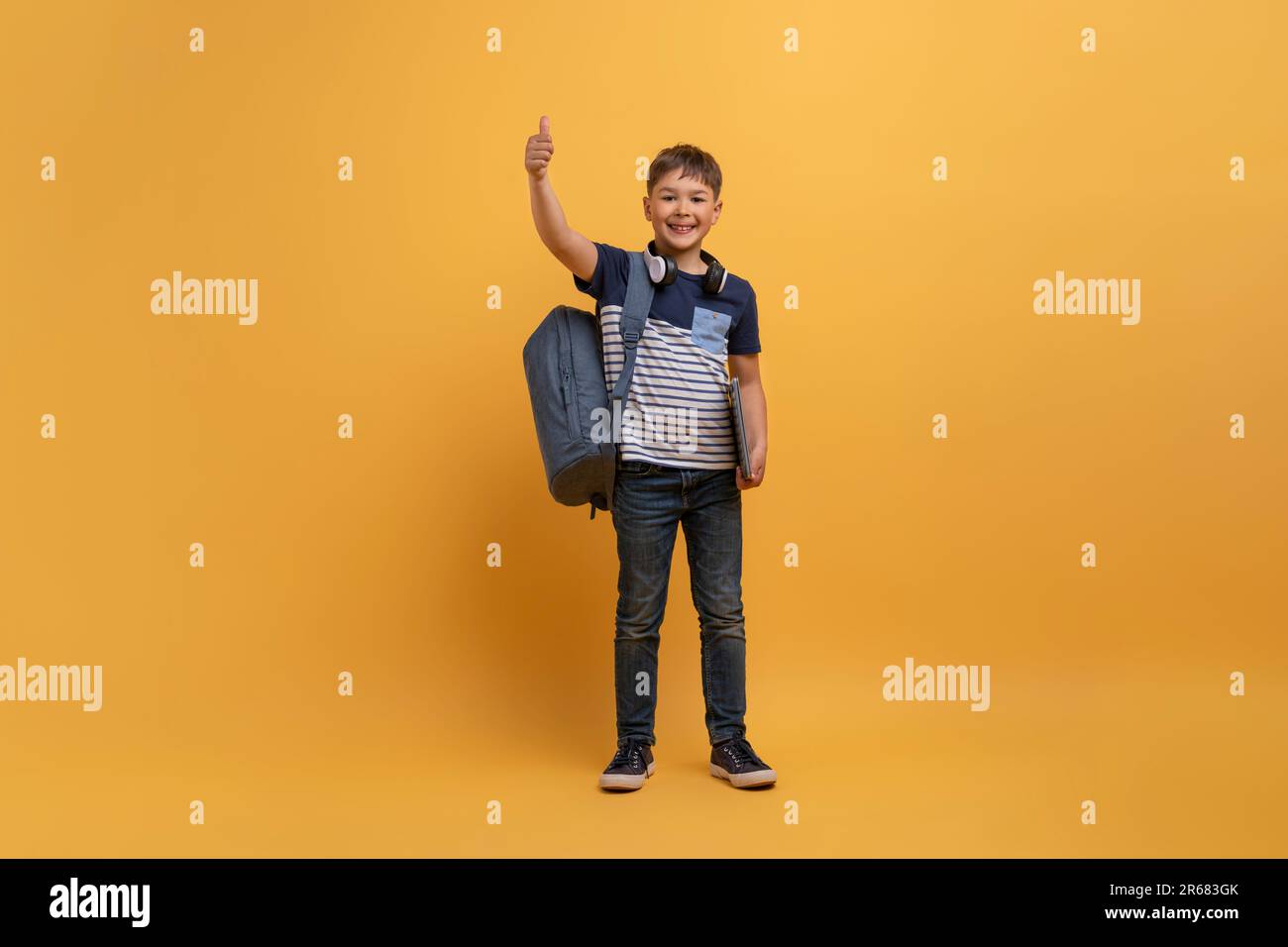 Cute handsome schooler boy showing thumb up on yellow Stock Photo - Alamy