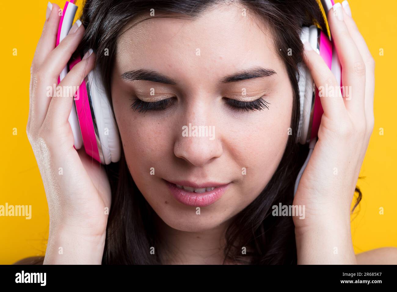 Young woman, semi-closed eyes, in headphones, deeply focused. Learning a foreign language or passionately listening to music, podcasts Stock Photo
