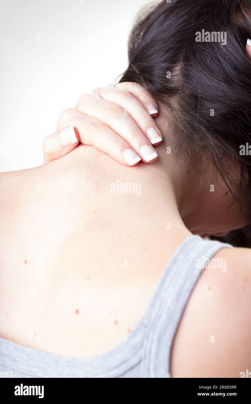 Woman massages neck's base above her back, troubled by cervical pain. Exercise and analgesics help headaches Stock Photo