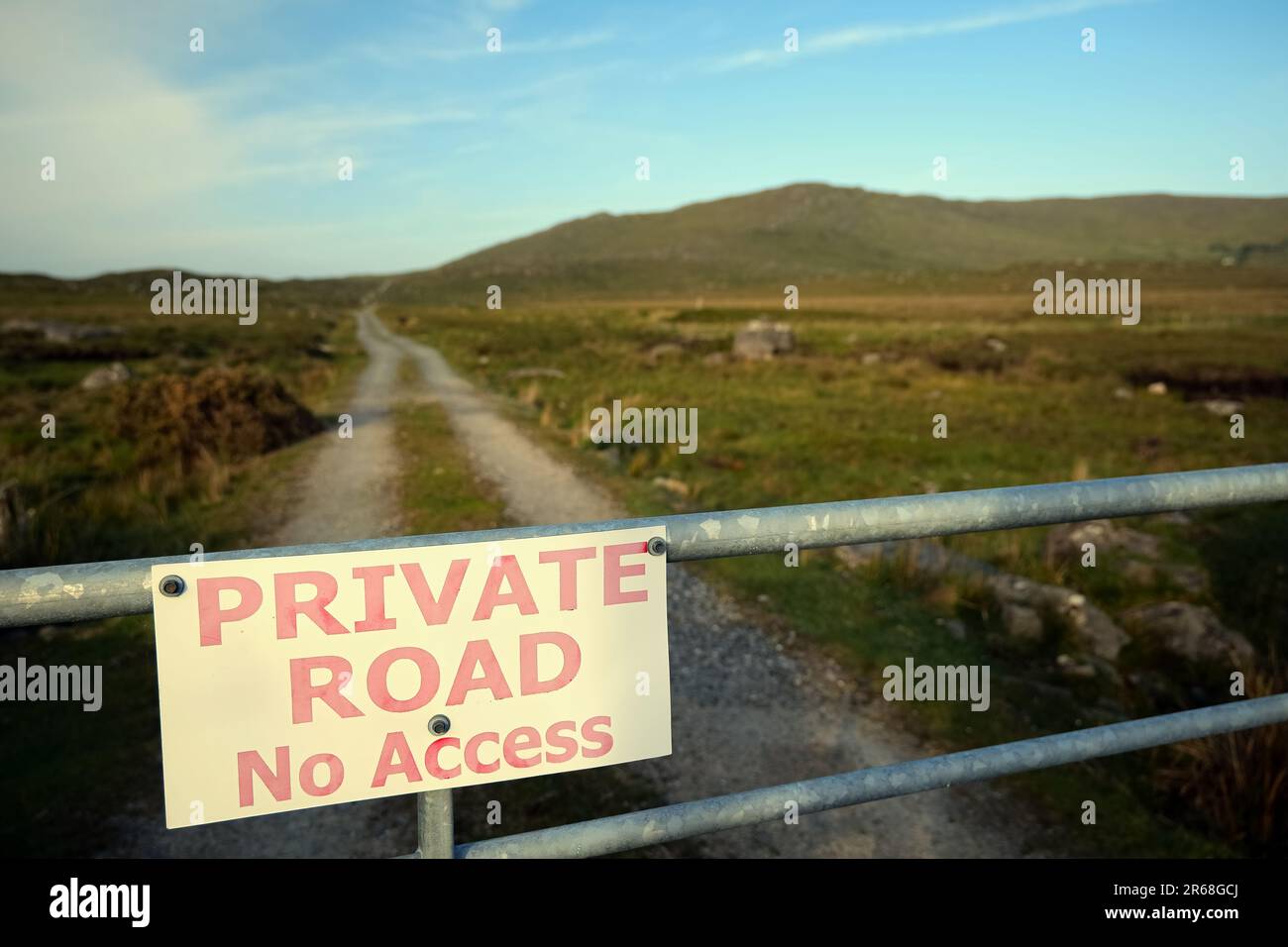 Closeup shot of sign private road, no access on the fence with country road and mountains in the background at Connemara National park, county Galway, Ireland Stock Photo