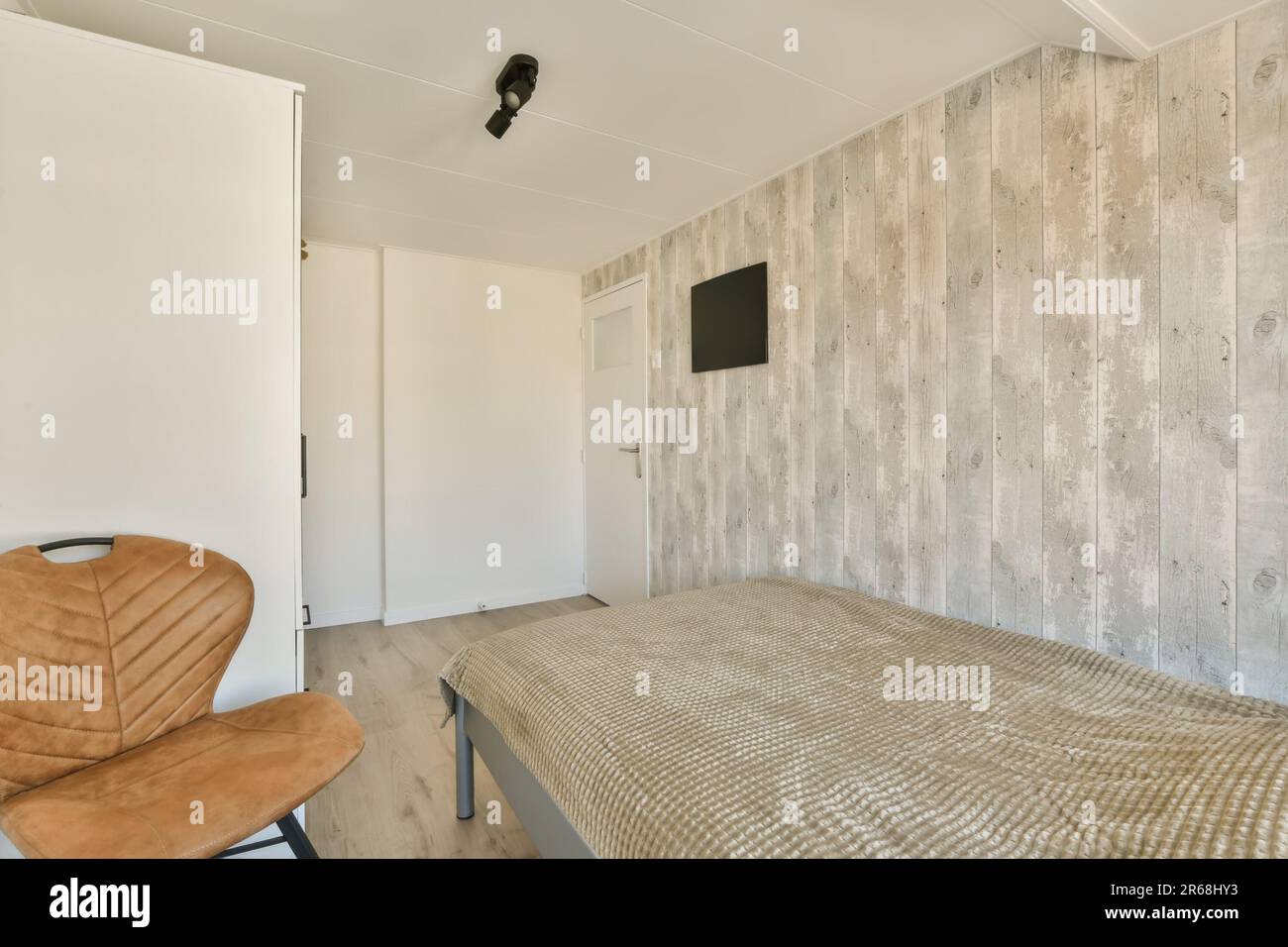 a bed in a room with wood paneling on the wall behind it is a brown