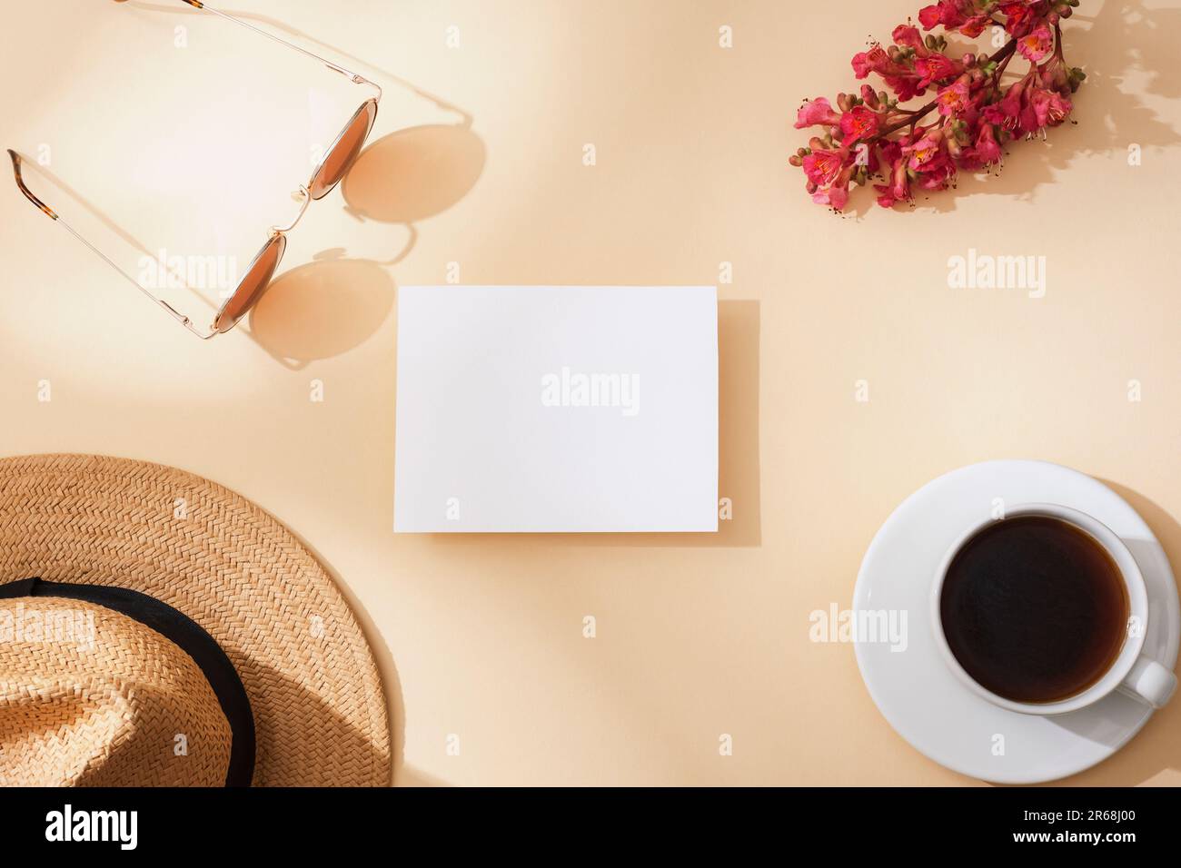 Blank card, coffee cup, straw hat, sunglasses and red flower. Top view, flat lay, mockup. Stock Photo