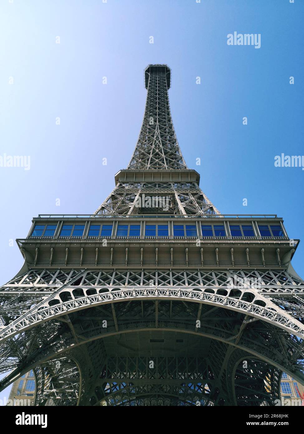 A vertical low angle shot of the Eiffel Tower under a clear blue sky ...