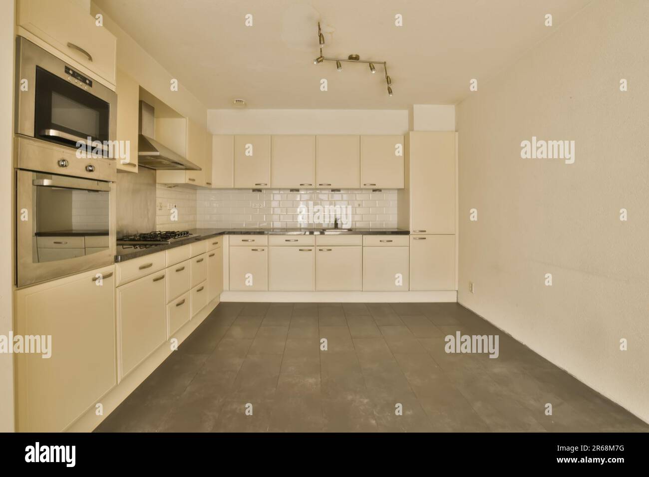 an empty kitchen with white cabinets and black counter tops on the ...