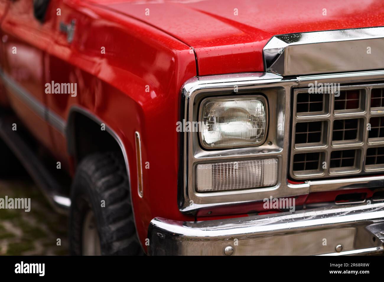 Izmir, Turkey - June 3, 2023: Close-up of the raindrop-covered headlight of a red 1980 Chevrolet Silverado truck at the IZKOD Classic Car Meet in Buca Stock Photo