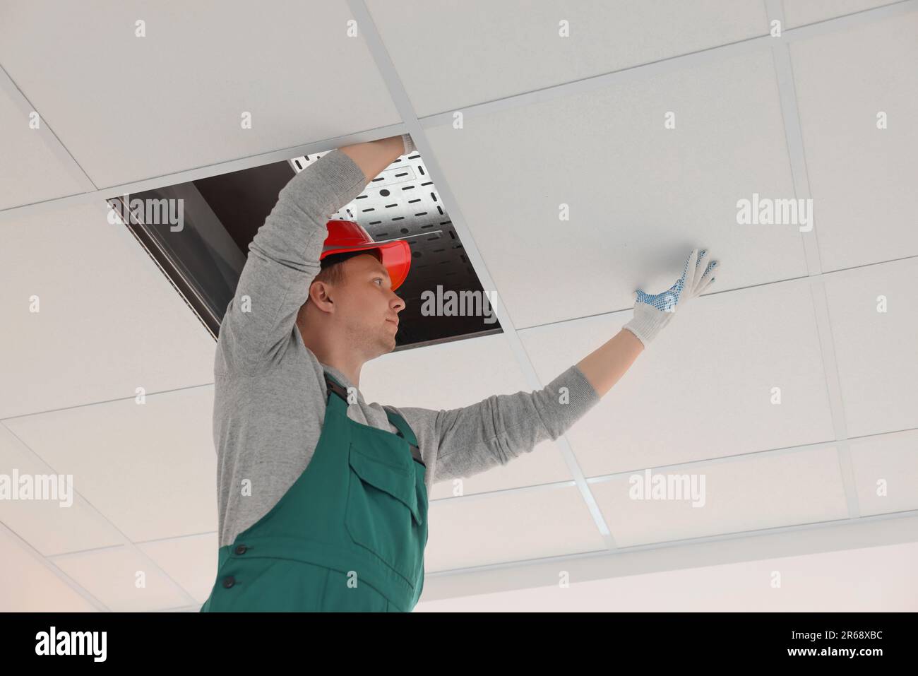 Suspended ceiling installation. Builder working with PVC tile Stock