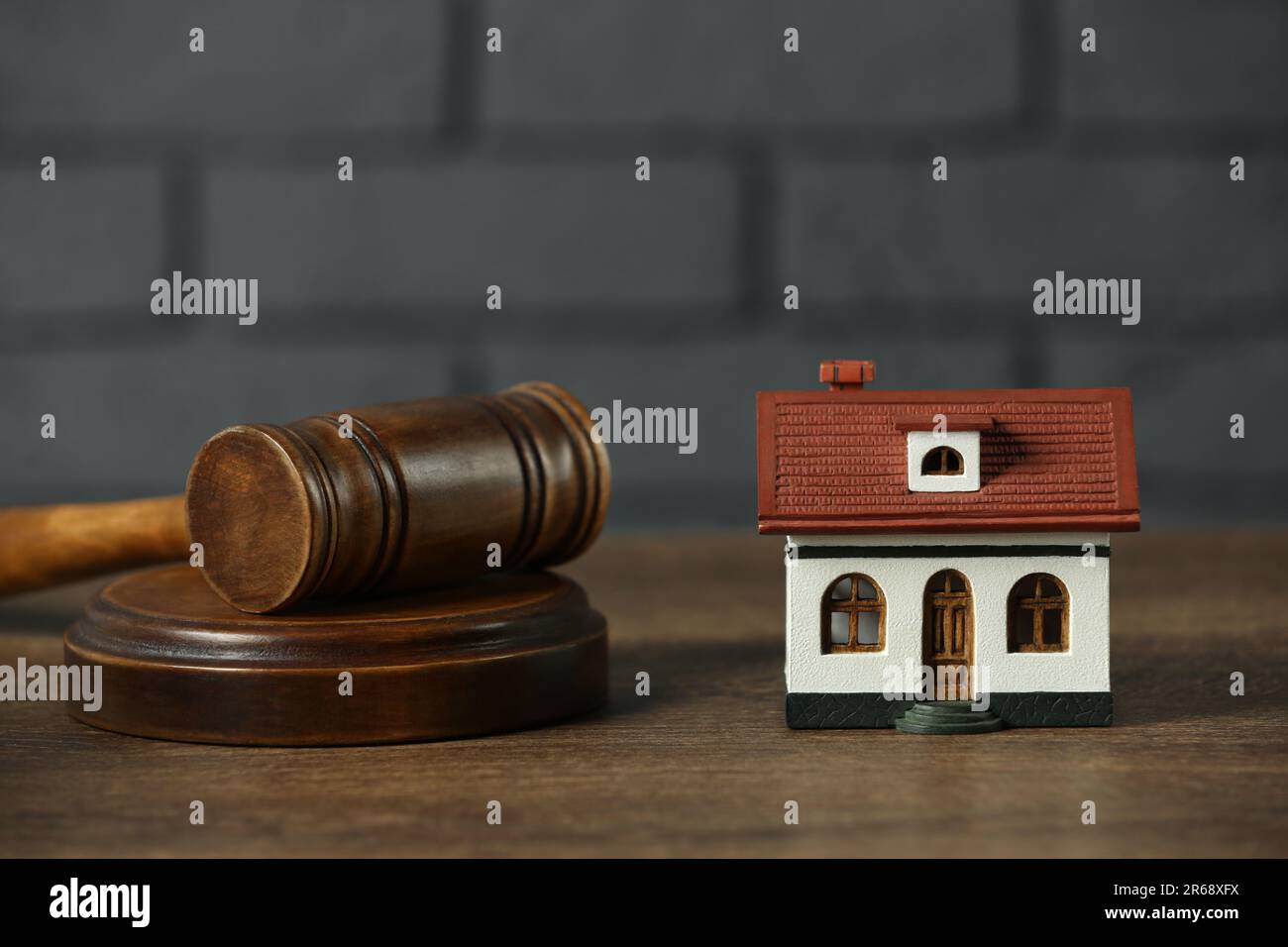 Construction and land law concepts. House model and gavel on wooden table, closeup Stock Photo