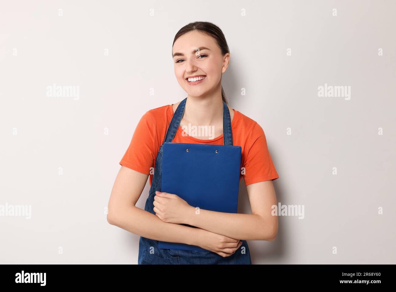 Beautiful young woman in clean denim apron on light grey background ...