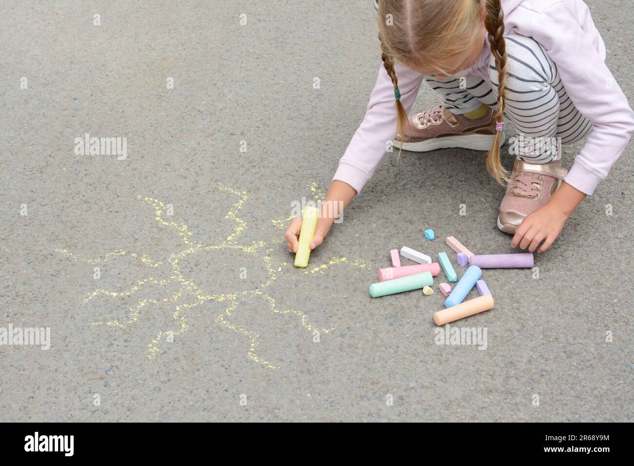 Little child drawing sun with chalk on asphalt Stock Photo - Alamy