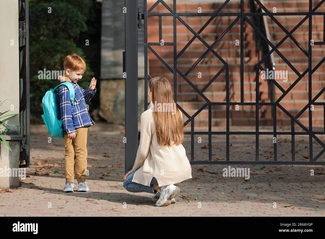 Little boy waving goodbye to his mother near school Stock Photo