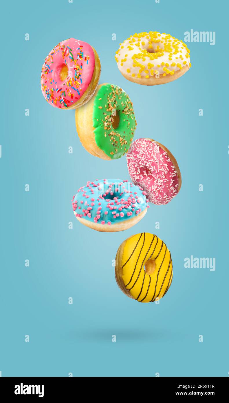 Sweet tasty donuts falling on light blue background Stock Photo