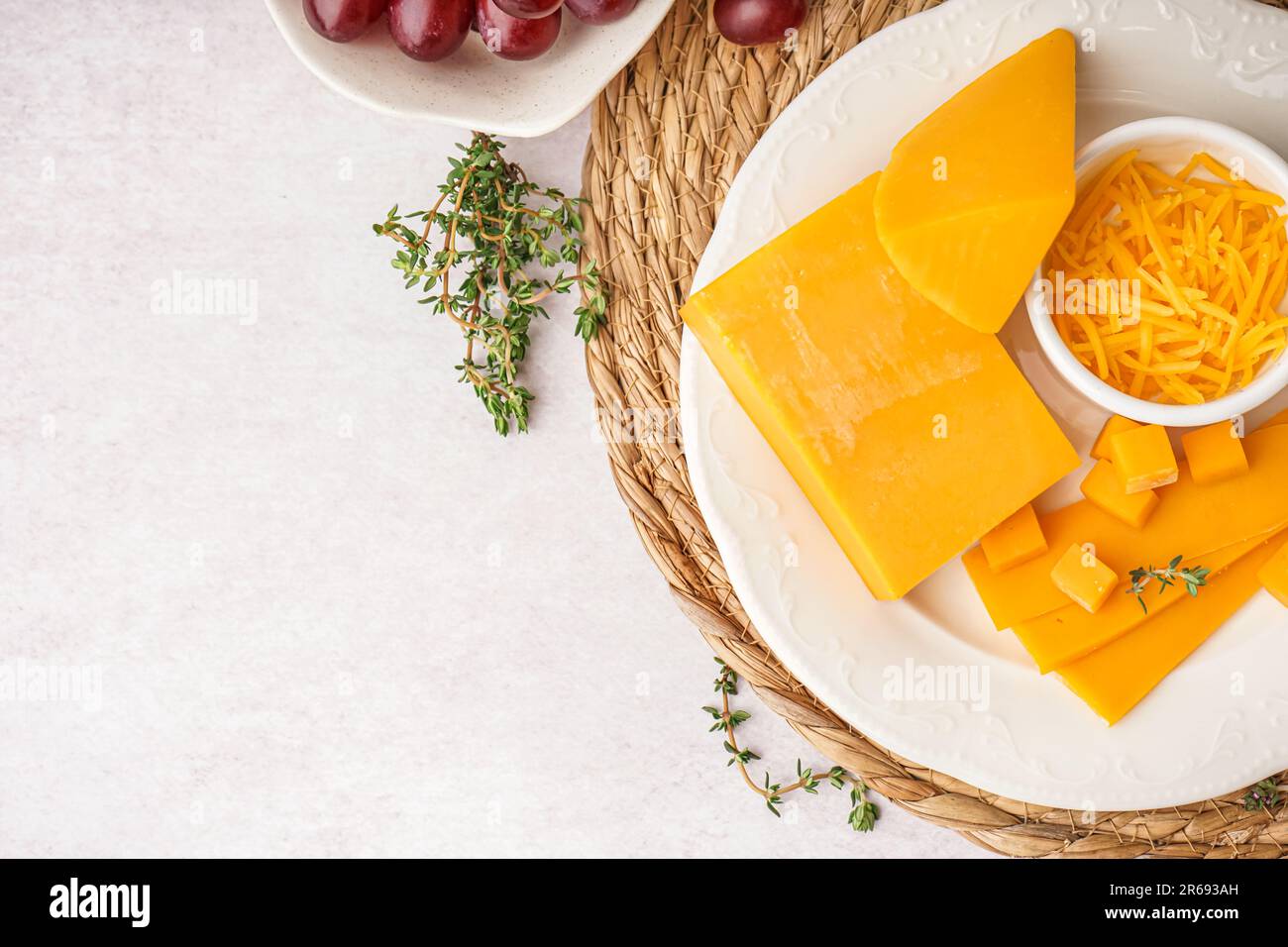 Plate with tasty cheddar cheese and grapes on light background Stock