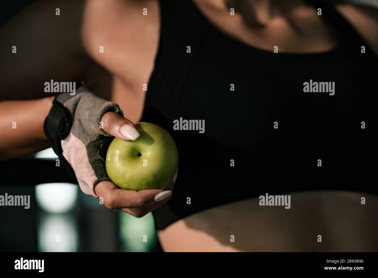 Close-up hands woman holding apple fruit after exercise workout in gym. Stock Photo