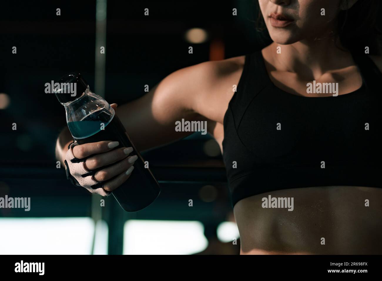 Sporty woman holding water bottle and resting after training in the gym. Stock Photo