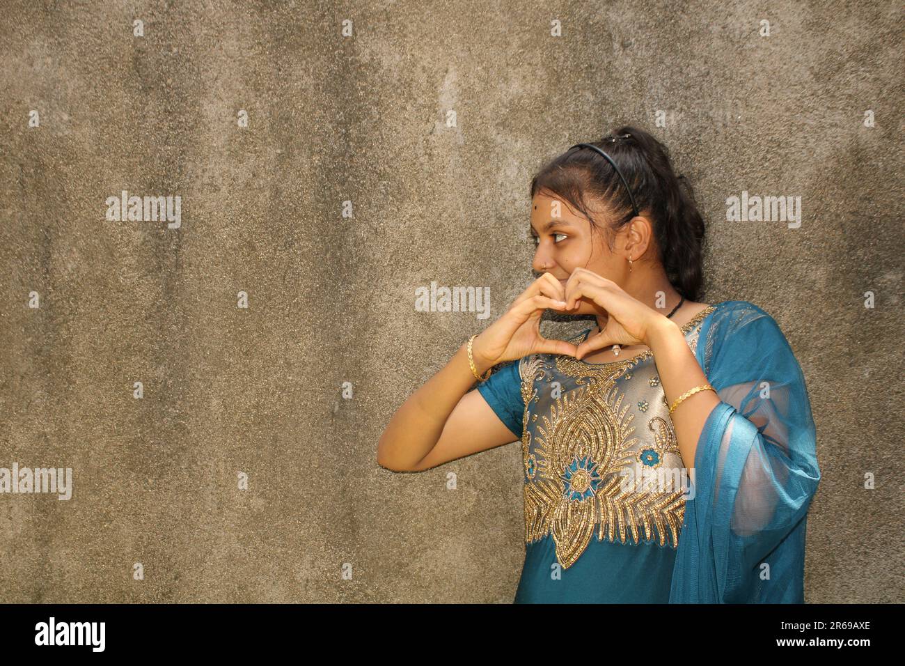 Portrait of a beautiful young teenage girl, Indian nationality. Against the background of the textural wall with copy space for text or word. Outdoors Stock Photo