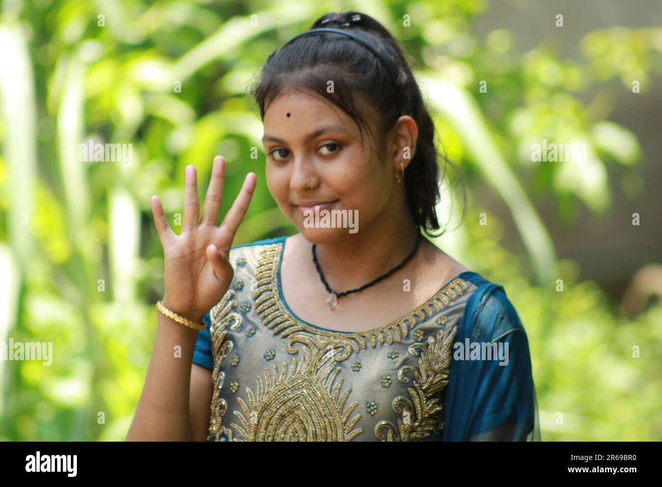 Indian Teenage Girl Showing And Pointing With Finger Number Four While Smiling Confident And