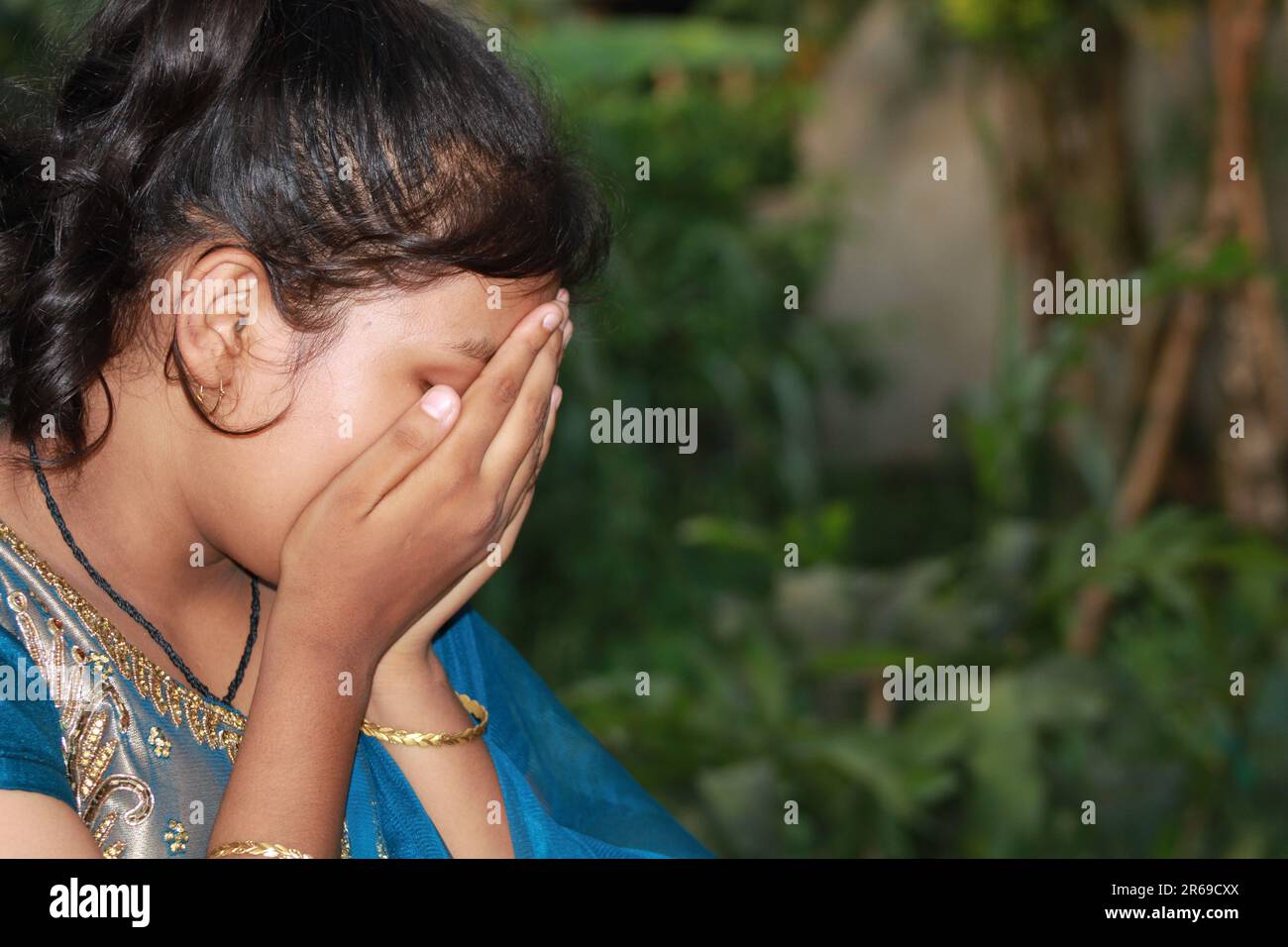 Portrait of a smiling Asian Indian Girl standing and looking at camera isolated . Covering his face with his hands. Stock Photo