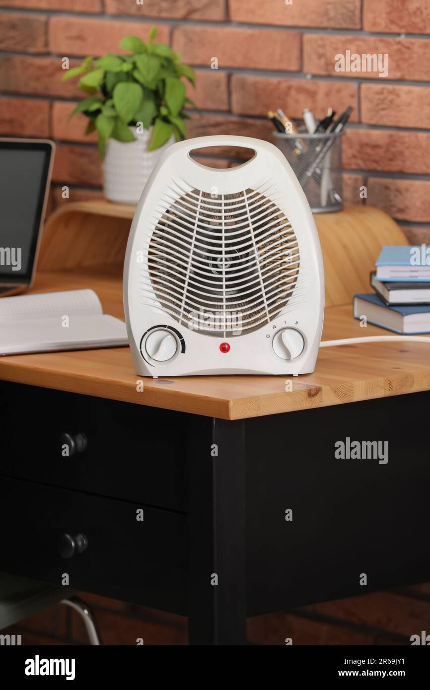 Modern electric fan heater near notebooks on wooden table in office Stock  Photo - Alamy
