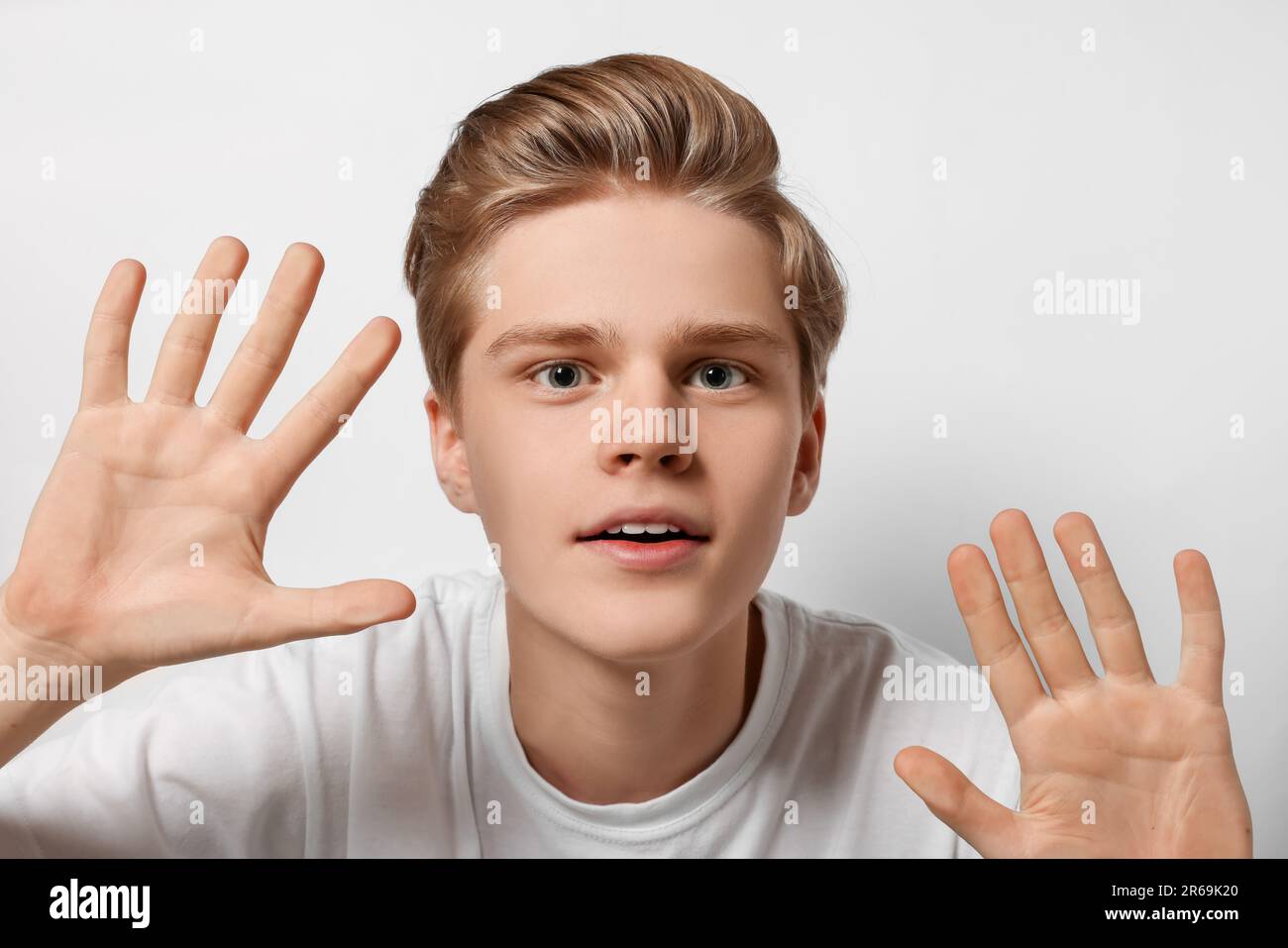 Excited teenage boy stuck to transparent screen Stock Photo