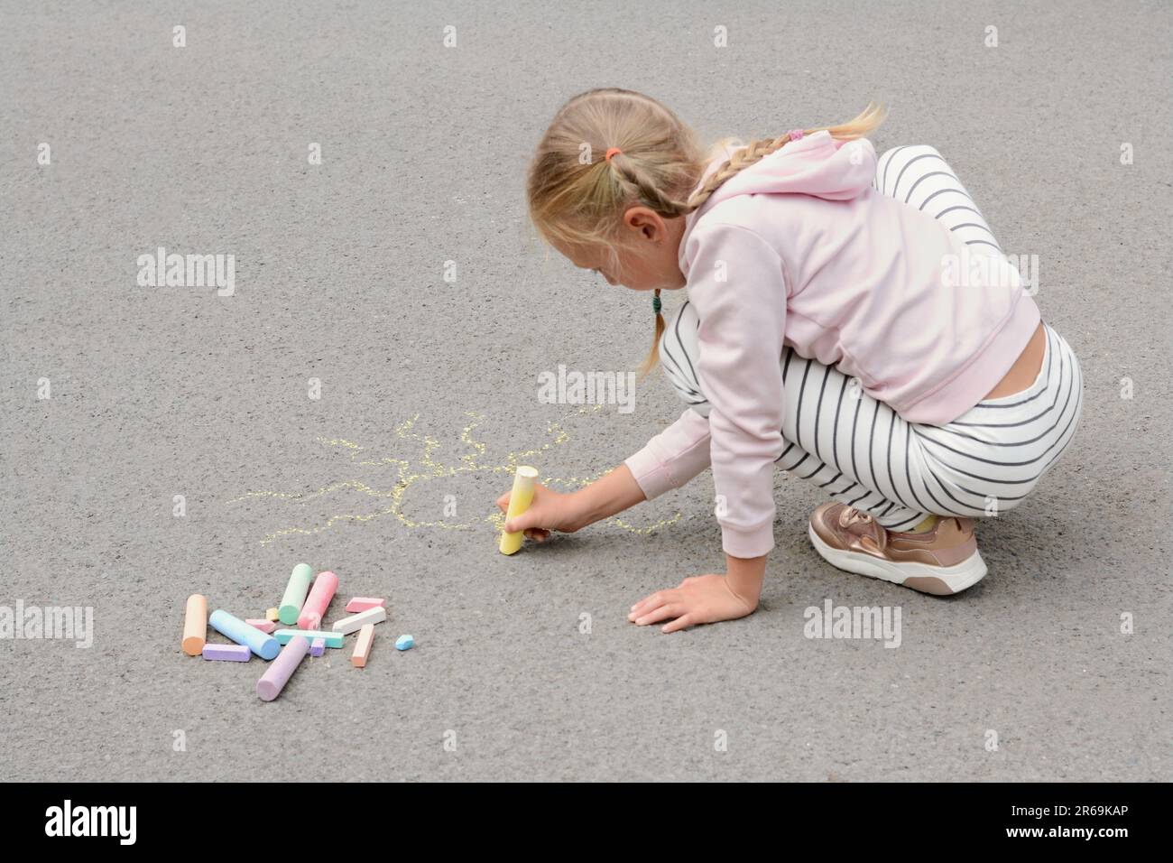 Little child drawing sun with chalk on asphalt Stock Photo - Alamy