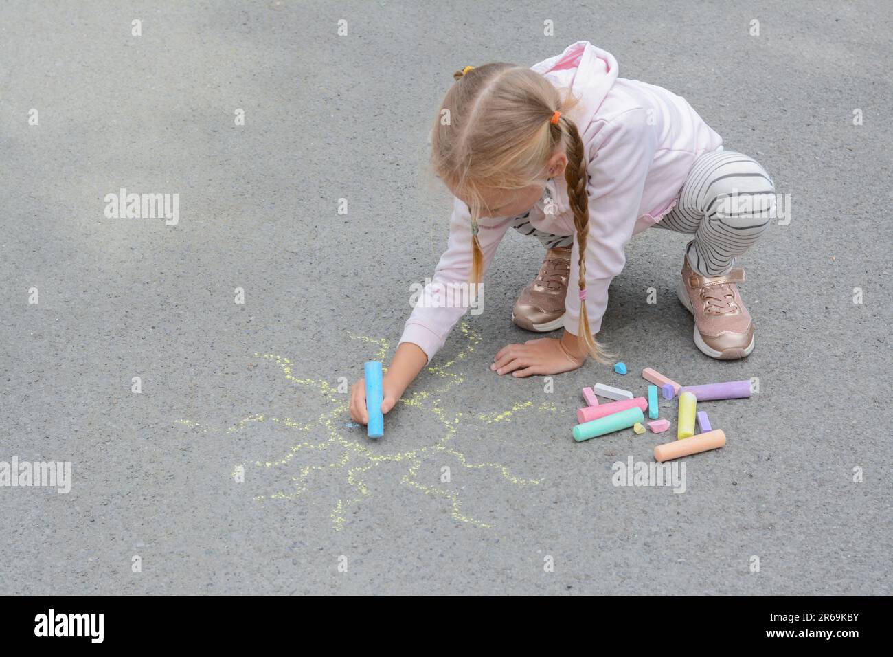 Little child drawing sun with chalk on asphalt Stock Photo - Alamy