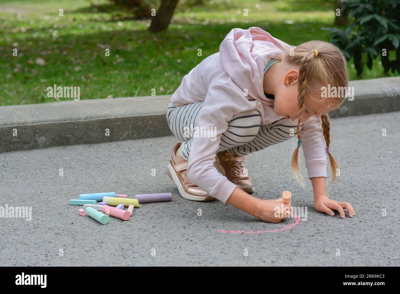 Little child drawing rainbow with chalk on asphalt Stock Photo - Alamy