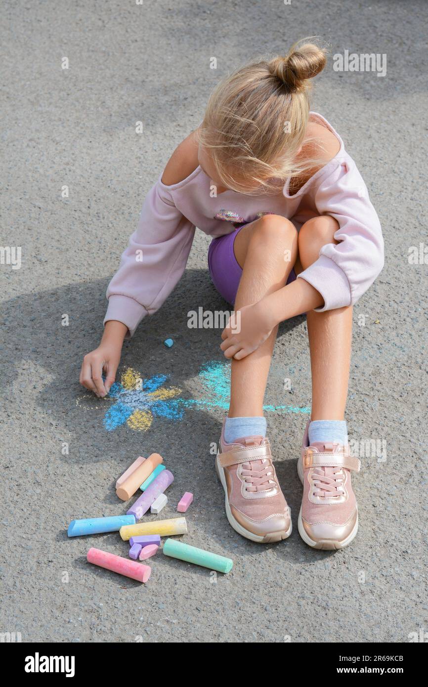 Little child drawing flower with chalk on asphalt Stock Photo - Alamy