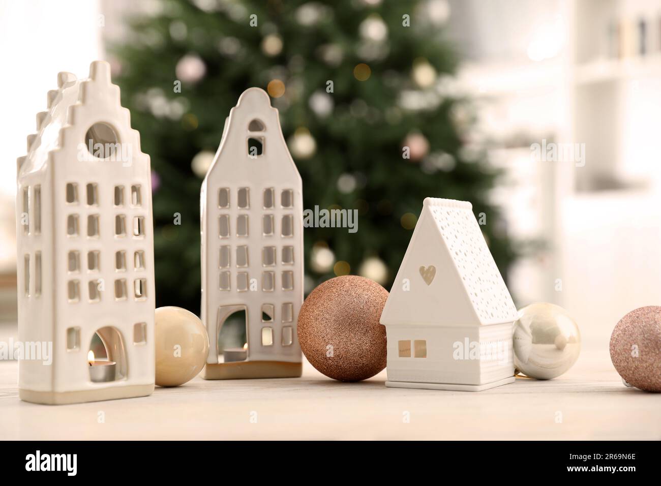 Beautiful house shaped candle holders and baubles on table indoors. Bokeh effect Stock Photo