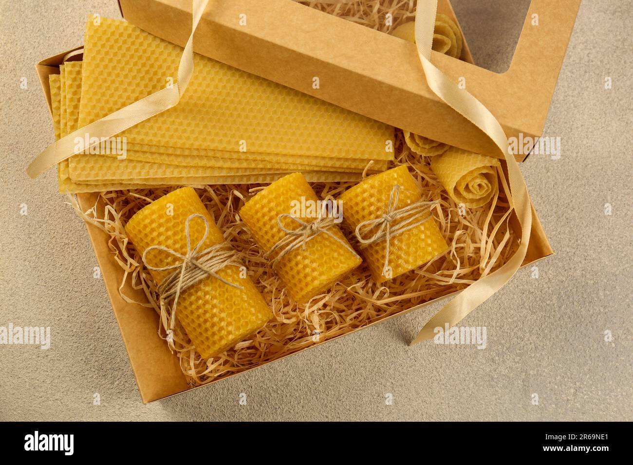 Beautiful yellow beeswax candles and sheets in box on light