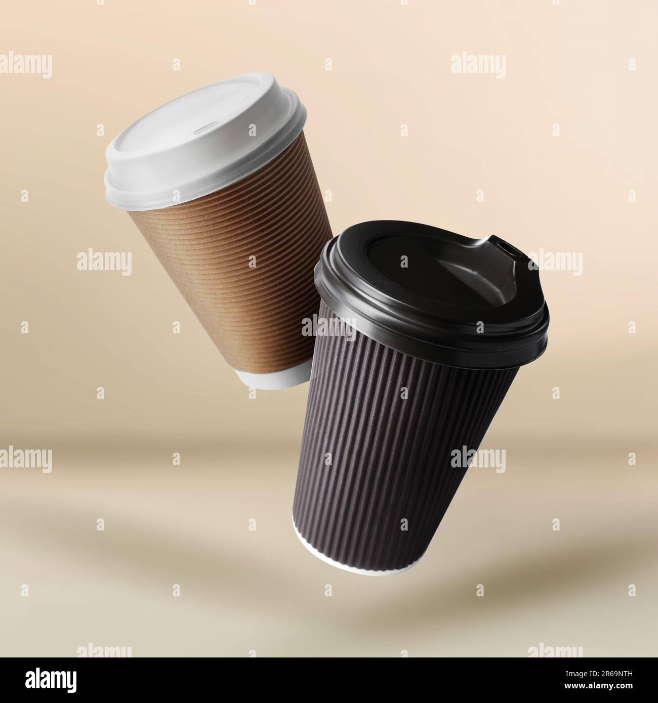 Takeaway paper cups falling on beige background Stock Photo