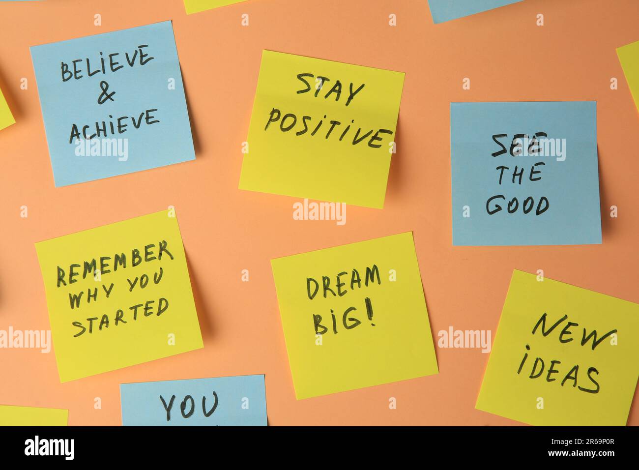 Paper notes with life-affirming phrases on pale orange background Stock Photo