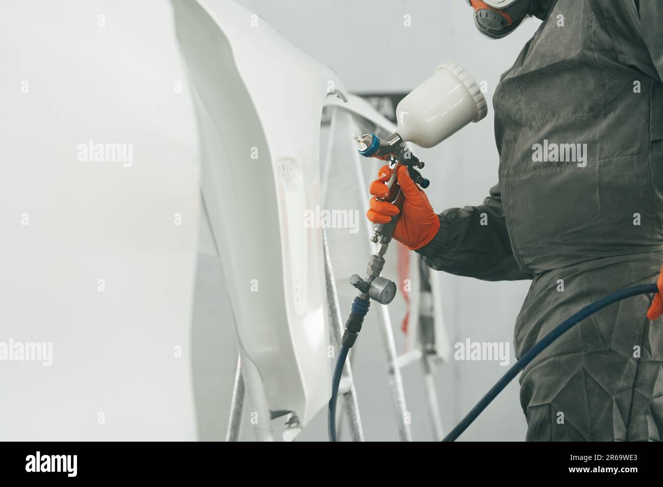 Auto painter painting a car with vaporizer gun inside a paint booth