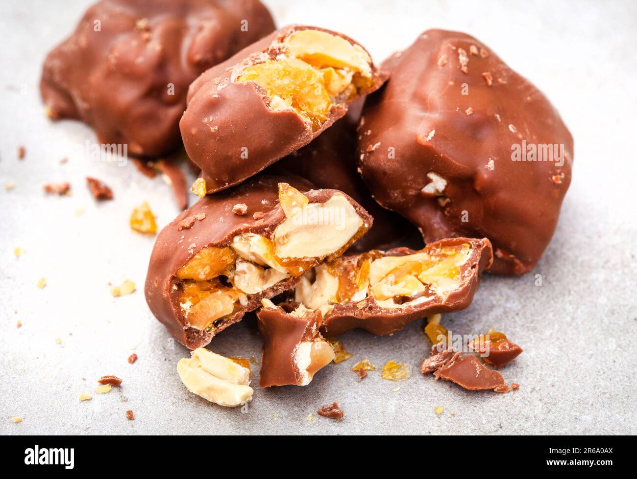Chocolate covered peanut brittle pieces on grey, white Stock Photo Alamy