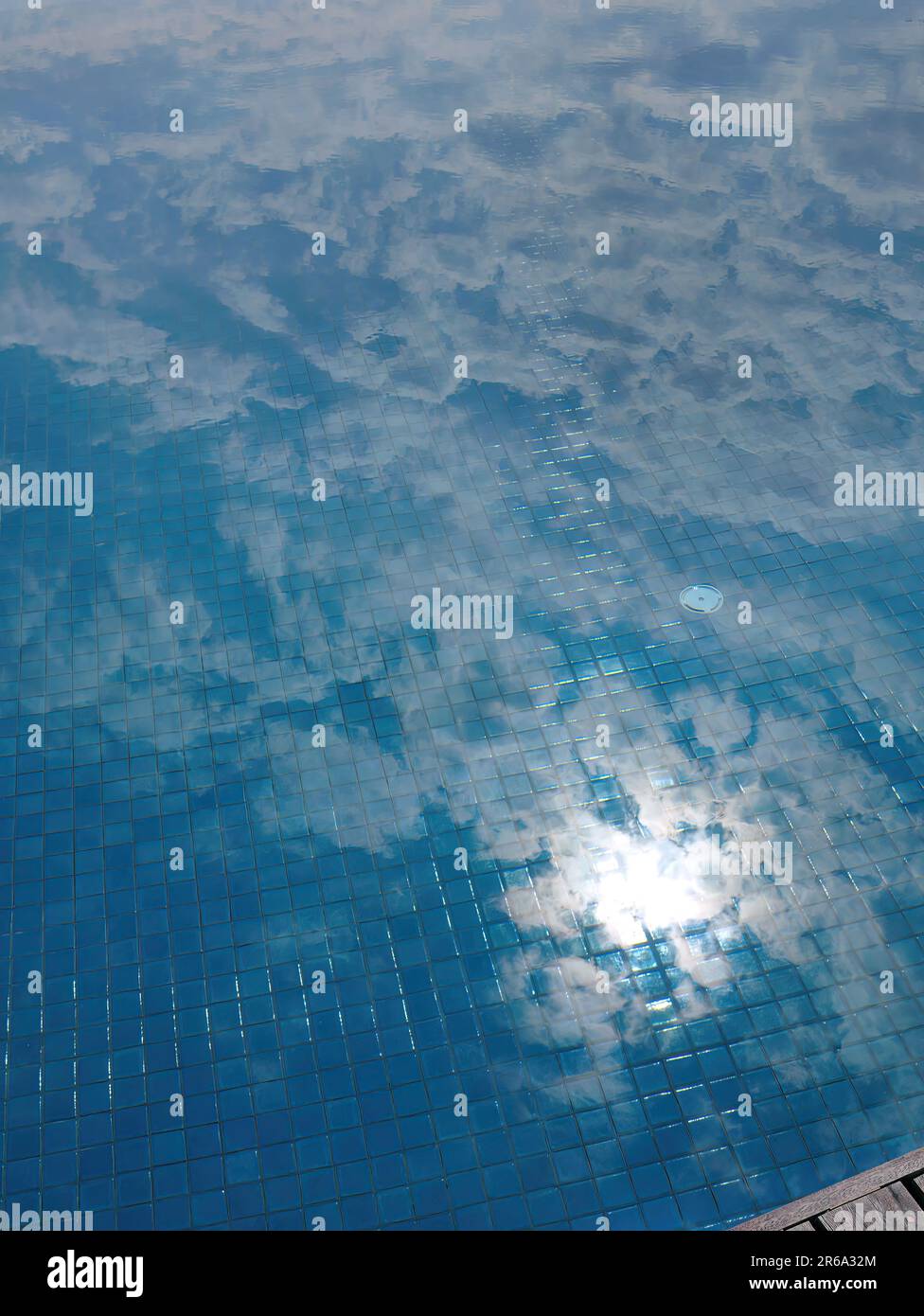 Mirror reflection of the sun, blue sky and clouds in the swimming pool, ceramic tiles texture, clear water, reflected, picture in the water, abstract Stock Photo