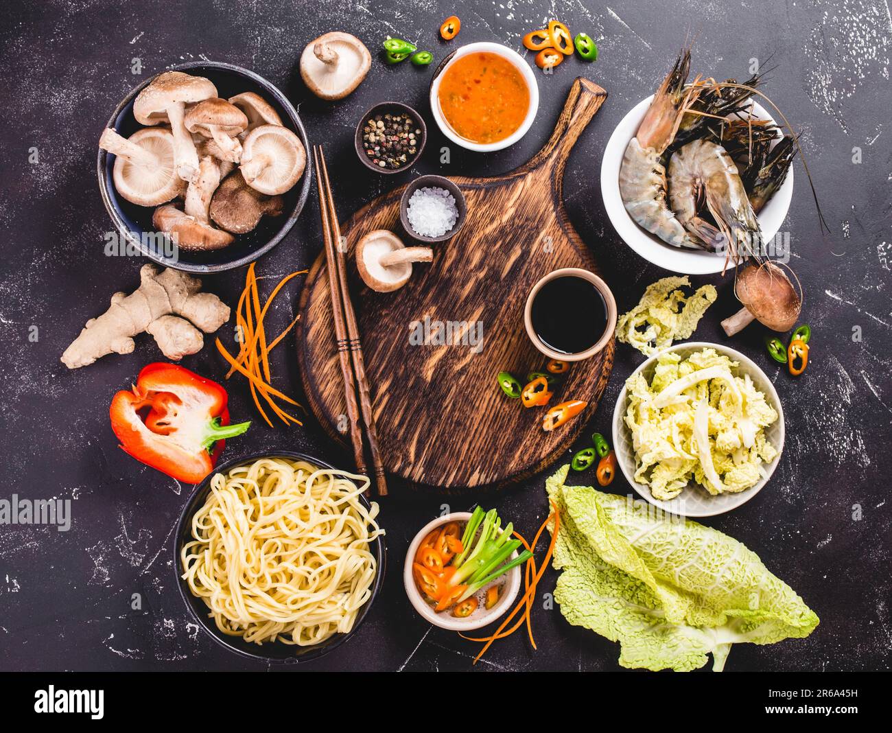 Asian food cooking concept. Empty wooden board, noodles, vegetables stir fry, shrimps, sauces, chopsticks. Asian/Chinese food. Top view. Ingredients Stock Photo