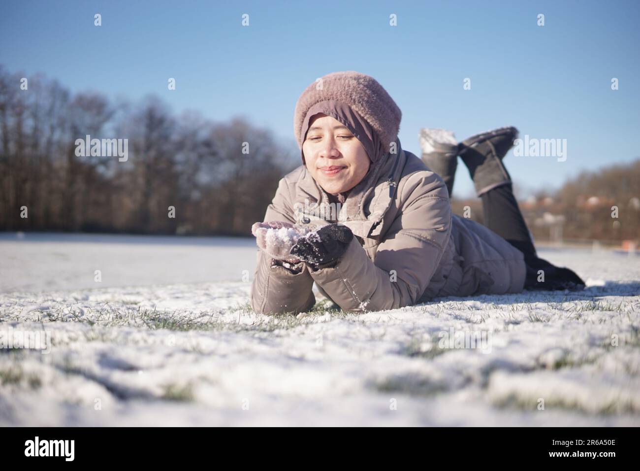 A female figure lies in the snow, her arm outstretched, clutching an unknown object Stock Photo