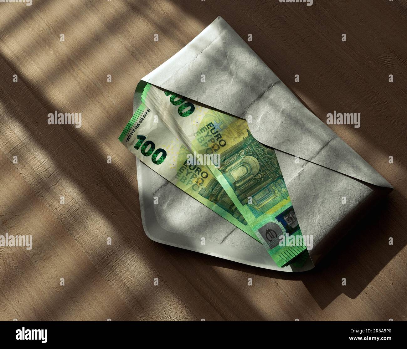 A spreading pile of euro banknotes in an envelope on a wooden surface ...