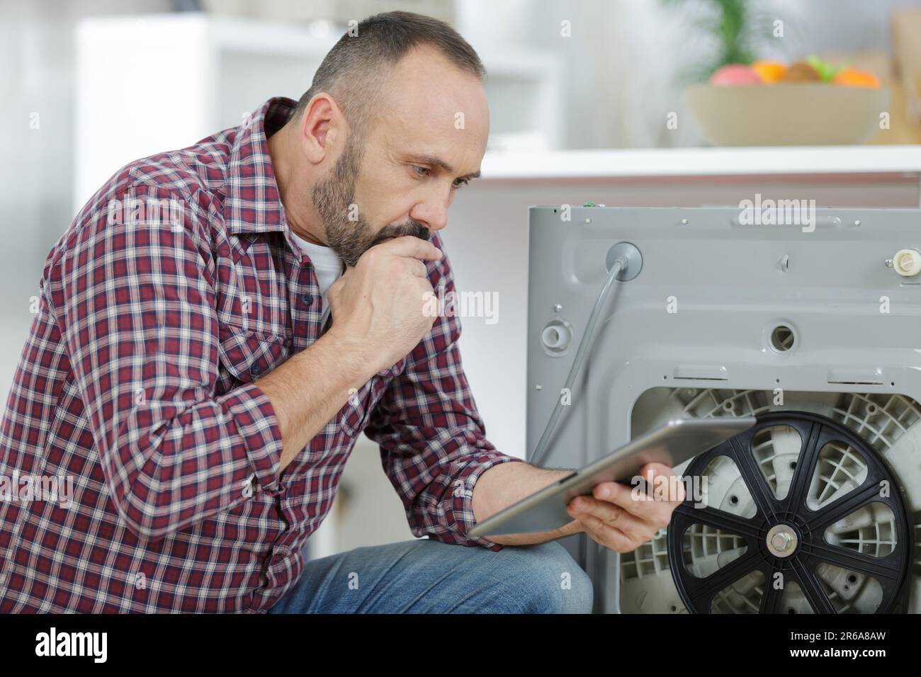man using tablet to fix a washing machine Stock Photo