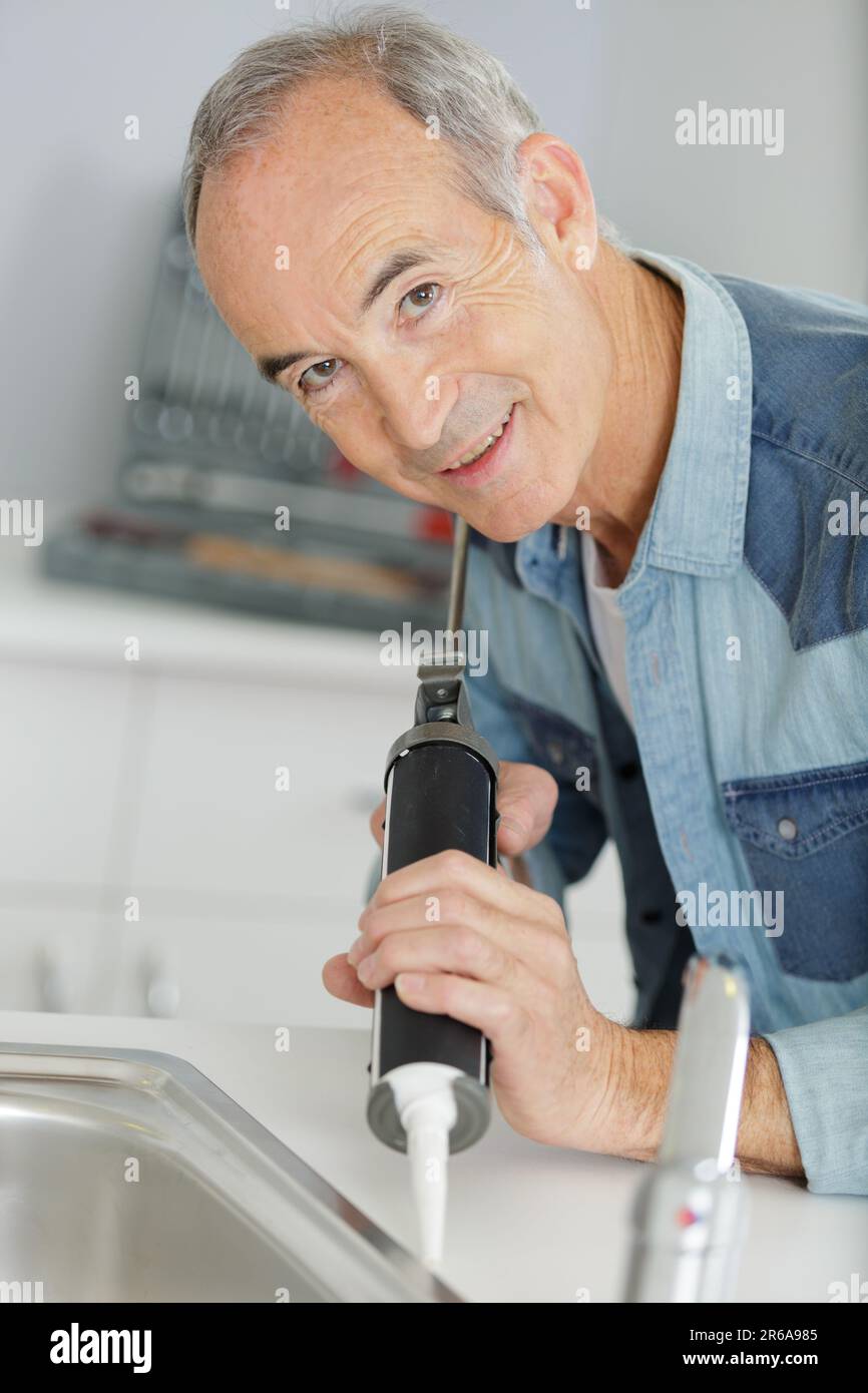senior repairs a leaky faucet Stock Photo