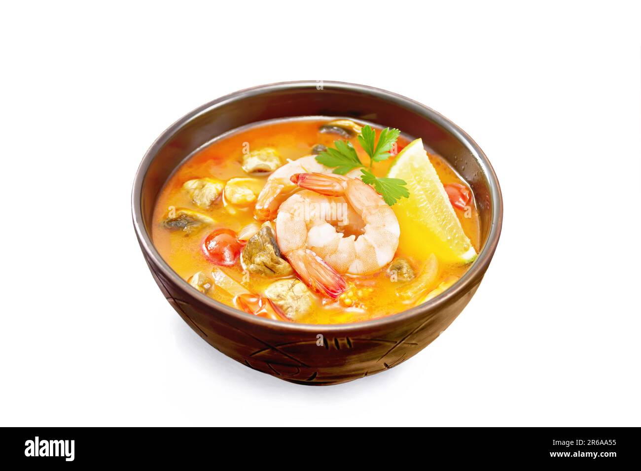 Thai soup Tom Yam from shrimp, chicken meat with mushrooms, tomatoes and lemon in a clay bowl isolated on a black background Stock Photo