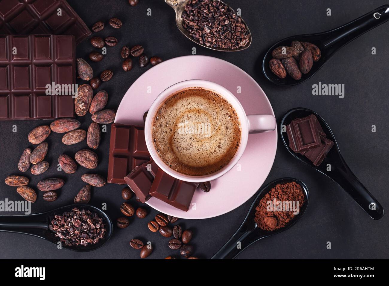 Aromatic cappuccino coffee cup with cafe beans, chocolate bar, cacao