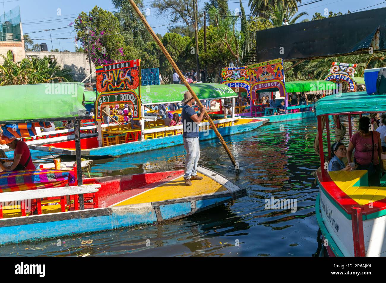 Popular tourist attraction people boating on colourful barges on canal at Xochimiloco, Mexico City, Mexico - trajinero punting barge Stock Photo