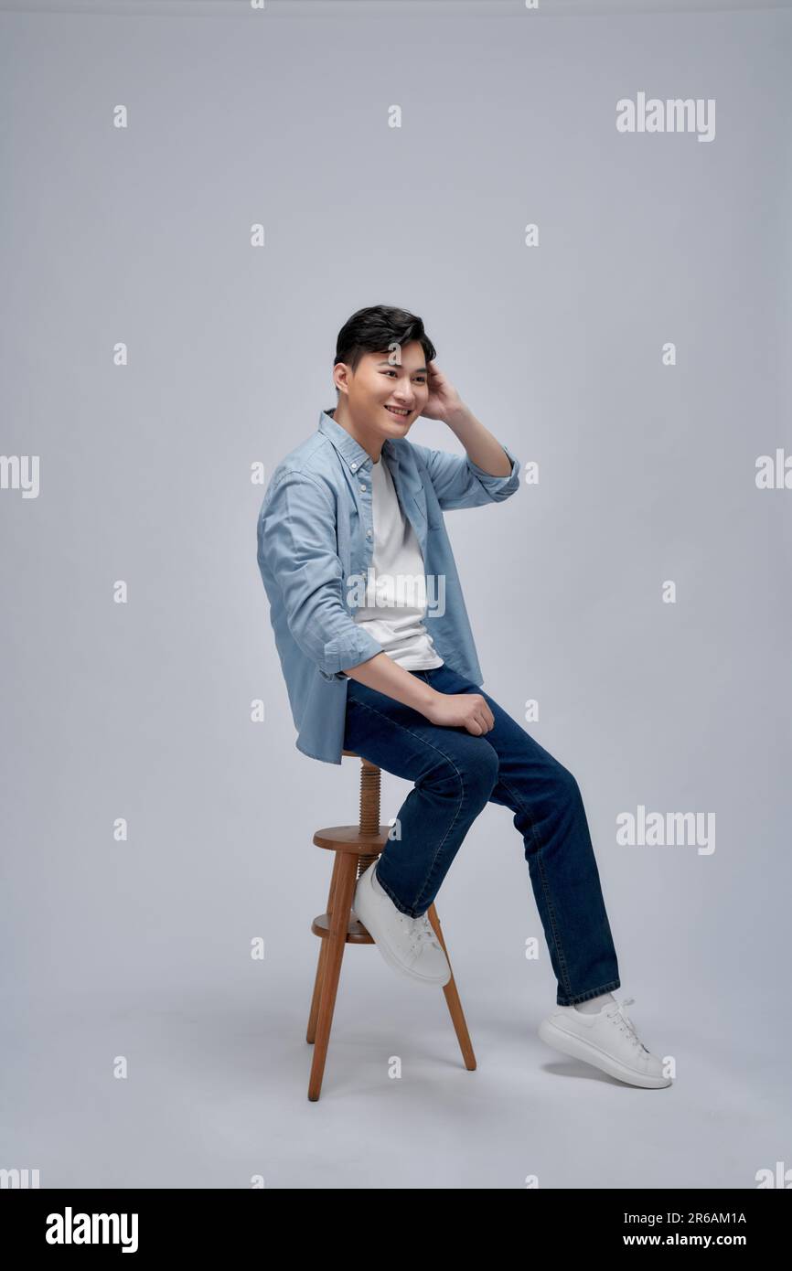 Handsome man sitting on stool against white background Stock Photo