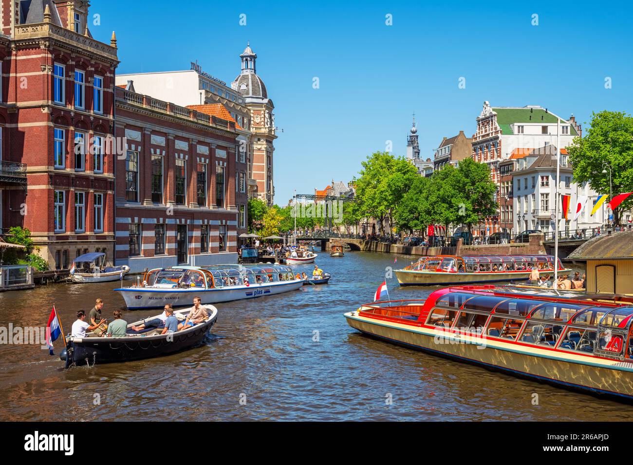Canal in Amsterdam, Netherlands busy with boat traffic on sunny saturday afternoon in June Stock Photo