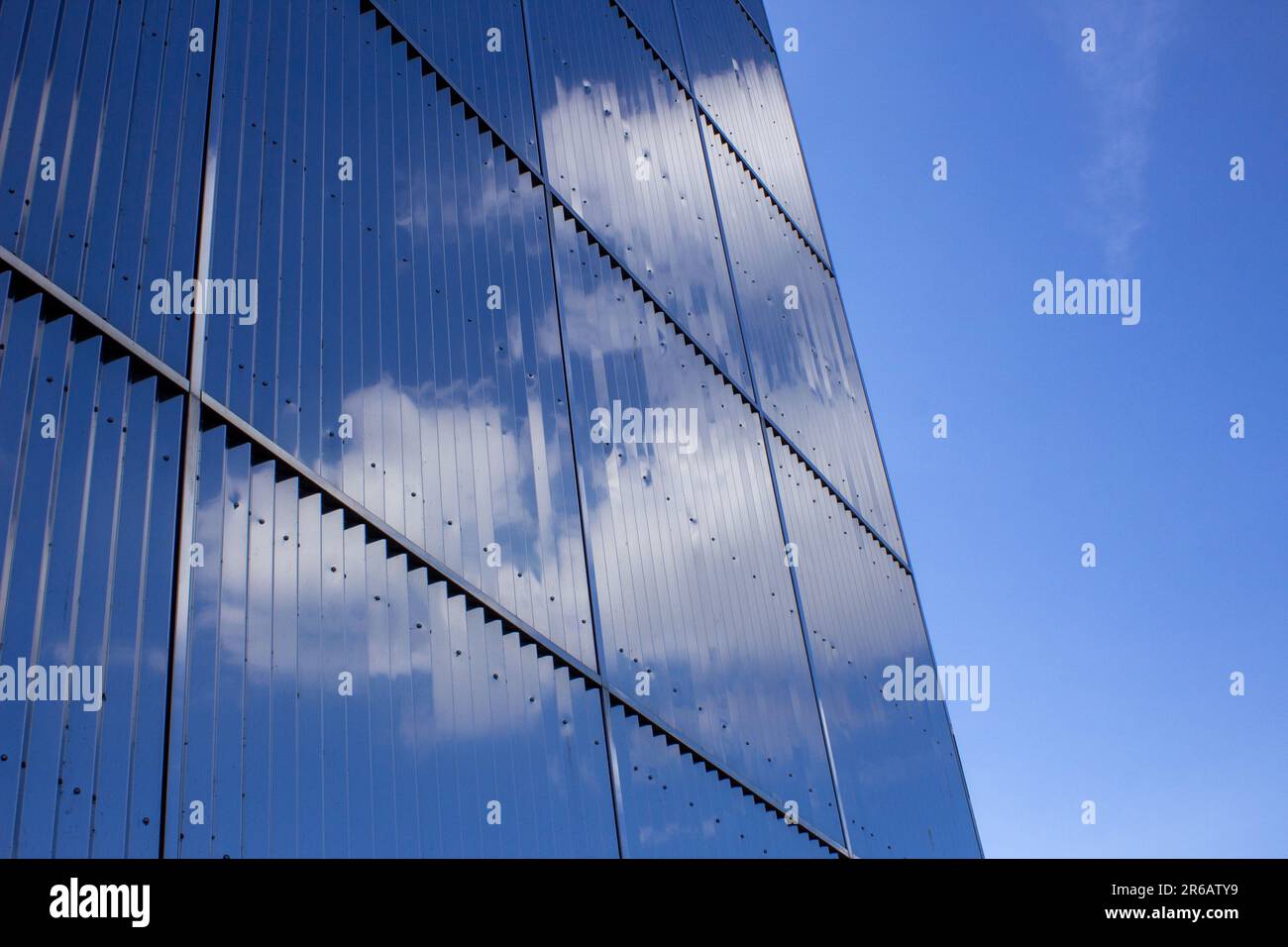 Clouds reflected in the sheer glass walls of an office block on a sunny day, taken in Milton Keynes, Buckinghamshire Stock Photo