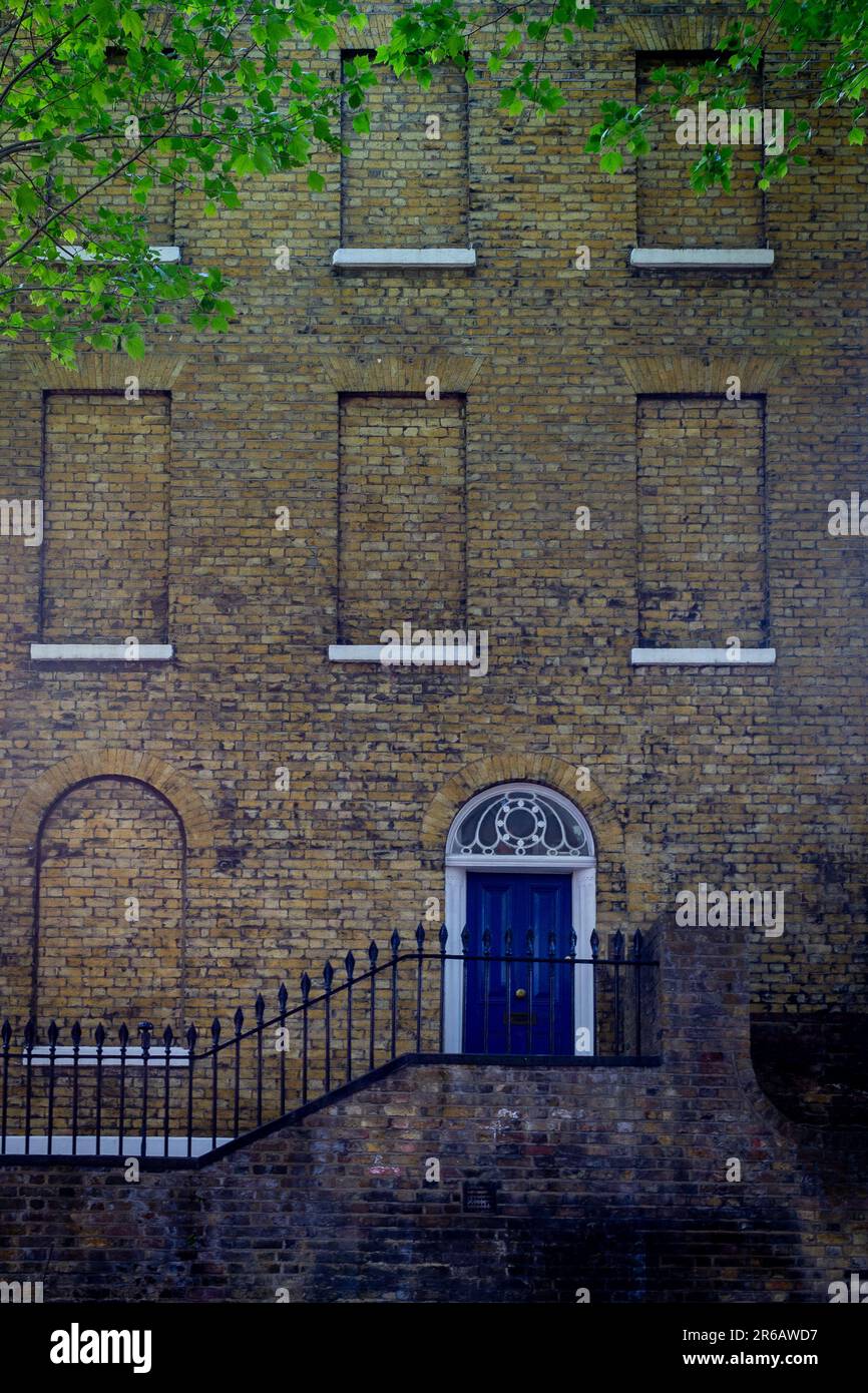 An elegant London Georgian town house with a blue front door up a flight of steps and all the windows bricked up - style feature or window tax? Stock Photo